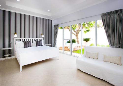 Dormitorio blanco con cama blanca y sofá en Tortuga Villas Pattaya en Pattaya South