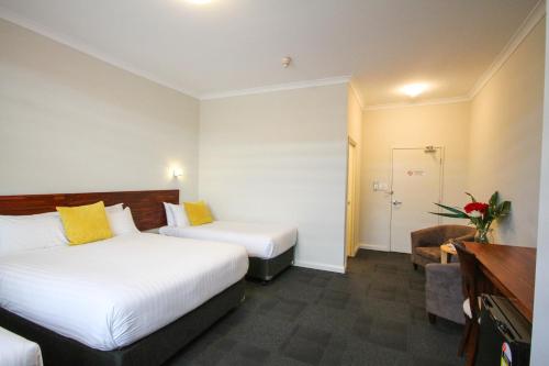 a hotel room with two beds and a bathroom at Gallery Hotel in Fremantle