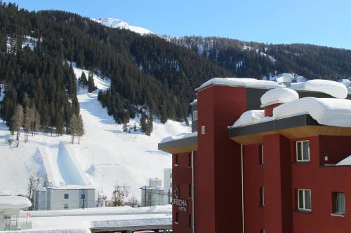 a red building with snow on top of a mountain at Grischa - Das Hotel Davos in Davos