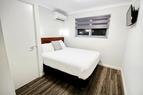 a small bedroom with a bed and a window at Gallery Hotel in Fremantle