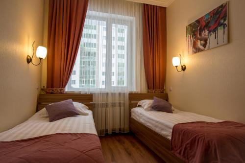 two beds in a hotel room with a window at MAXX inn in Astana