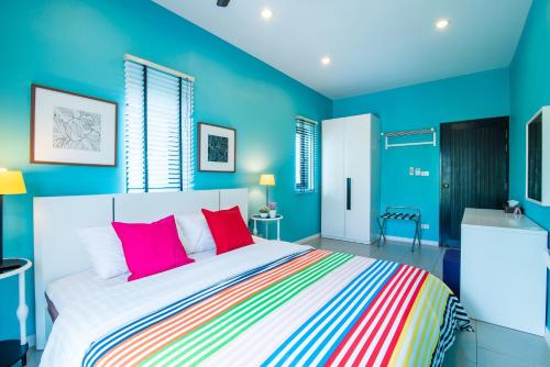 a bedroom with blue walls and a bed with red pillows at Villa Na Pran, Pool Villa in Pran Buri