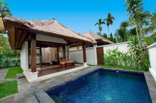 a villa with a swimming pool in front of a house at Pertiwi Resort & Spa in Ubud