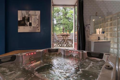 a bath tub filled with water in a room at Hotel La Font Vineuse & Spa in Saint-Pierre-dʼArgençon