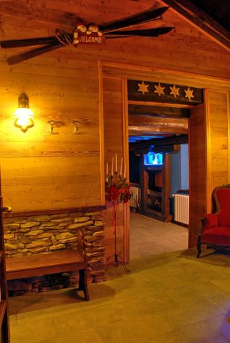 a log cabin with a fireplace and a red chair at Hotel Edelweiss & SPA in Cesana Torinese