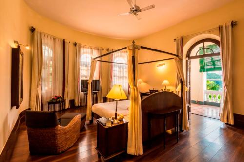 a bedroom with a canopy bed and a chair at Royal Orchid Brindavan Garden Mysore in Belagula