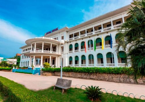 a white building with a bench in front of it at Royal Orchid Brindavan Garden Mysore in Belagula