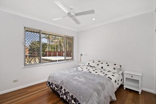 a white bedroom with a bed and a window at 143 Matthew Flinders Drive, Port Macquarie in Port Macquarie
