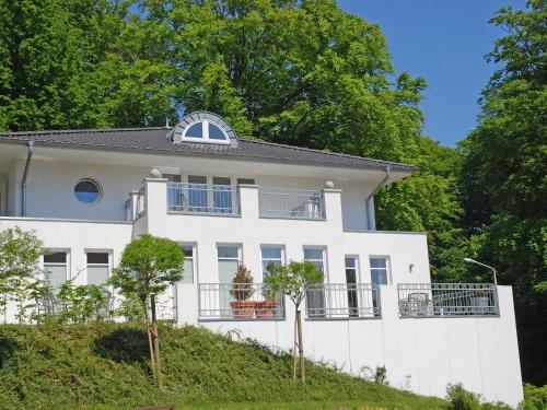 una casa blanca en una colina con árboles en Villa am Park - Apt. 02 Düne, en Ostseebad Sellin