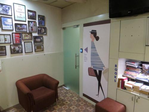 a waiting room with a chair and a poster of a woman at Smyle Inn - Best Value Hotel near New Delhi Station in New Delhi