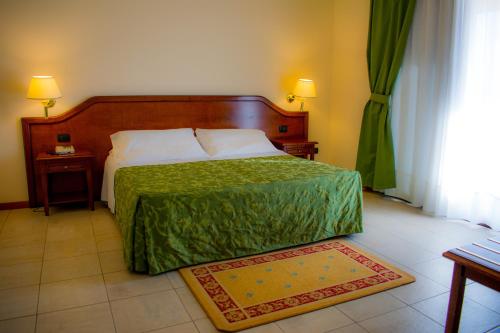 a bedroom with a bed with a green comforter at Hotel Villa Peretti in Gela