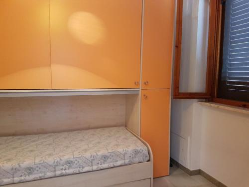 Piccola camera con parete arancione e letto piccolo. di Casa vacanza Andrea a Porto Cesareo