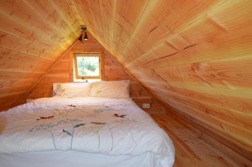 ein Schlafzimmer mit einem Bett in einer Holzhütte in der Unterkunft First Light Rangihaeata Retreat in Takaka