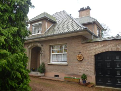 een bruin bakstenen huis met een zwarte garage bij au vieux cèdre in Mouvaux