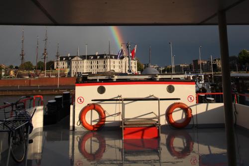 a boat with orange life rings on it with a rainbow in the background at Hotelboat Angeline in Amsterdam