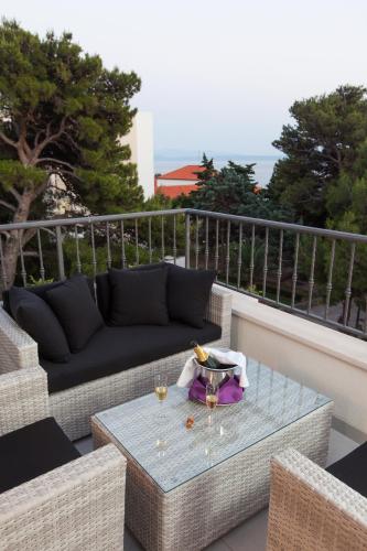 a patio with a couch and a table with wine glasses at Apartmani Pašalić in Tučepi