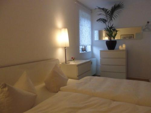 a bedroom with a bed and a dresser with a potted plant at SchlossparkFerienwohnungen Rheinsberg mit Garten in Rheinsberg