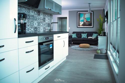 a kitchen with white cabinets and a living room at Penthouse "Meerzeit" Kellenhusen mit Strandkorb in Kellenhusen