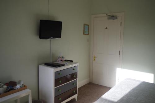 a bedroom with a dresser with a tv on the wall at Varley House in Ilfracombe