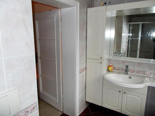 ein weißes Badezimmer mit einem Waschbecken und einem Spiegel in der Unterkunft Ferienwohnung Hoffmann in Rathmannsdorf