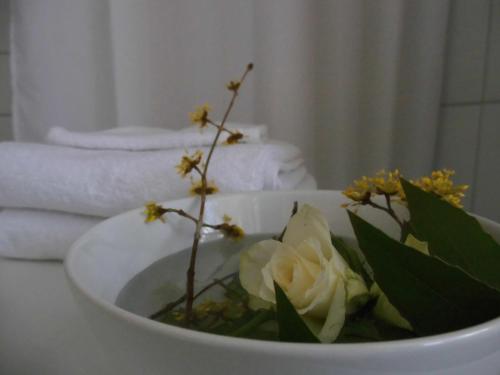 a white bowl with flowers in it on a table at SchlossparkFerienwohnungen Rheinsberg mit Garten in Rheinsberg