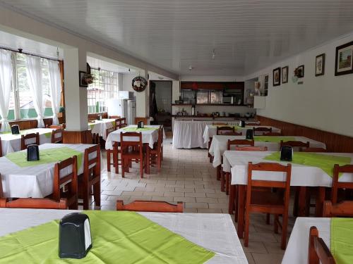 a dining room with tables and chairs with green covers at Pousada Miniférico in Campos do Jordão