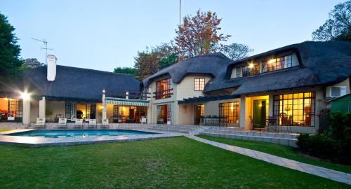 a large house with a pool in the yard at Thatchfoord Lodge in Johannesburg