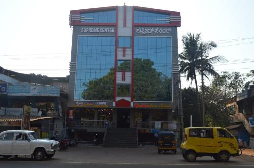 a tall building with cars parked in front of it at SUPREME LODGe in Dharmastala