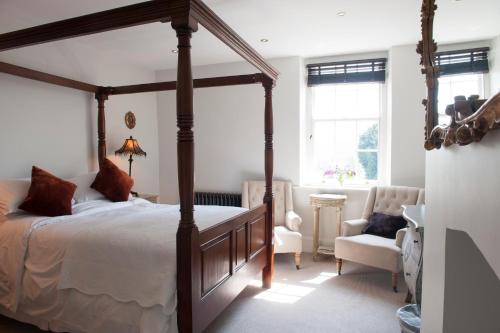 een slaapkamer met een groot hemelbed en een stoel bij The Bridge House in Ross on Wye