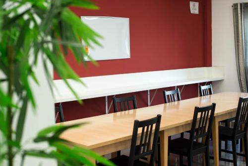 a classroom with a table and chairs against a red wall at Hotel Cim Valles in Santa Perpetua de Moguda