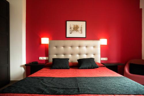 a red bedroom with a large bed with a red wall at Hotel Cim Valles in Santa Perpetua de Moguda