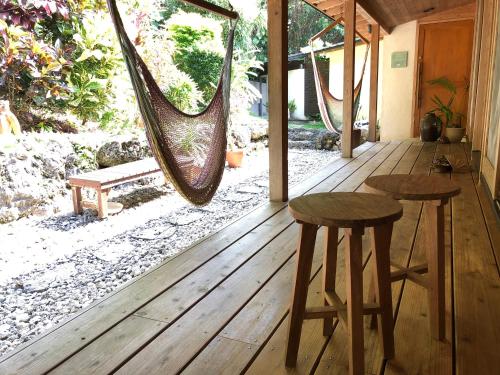 a porch with two hammocks and a table and two stools at Kaiza in Nanjo