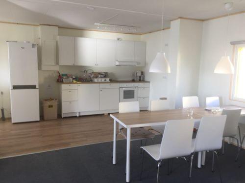 a kitchen with white cabinets and a table and chairs at Giljanes Hostel in Sandavágur