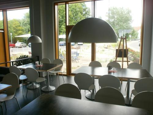 a restaurant with tables and chairs and a large light fixture at veloInn Hotel Bad Berka im Weimarer Land in Bad Berka