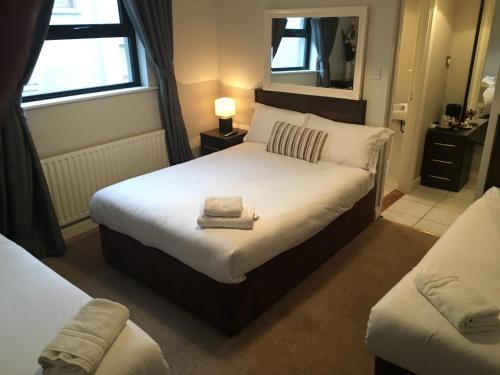 1 dormitorio con 1 cama blanca grande y 2 ventanas en The Midway Bar & Guesthouse en Dungloe