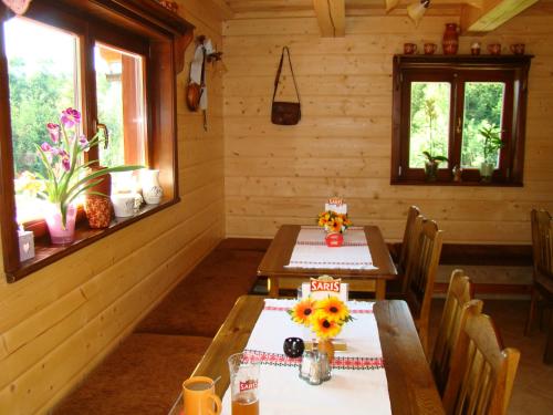 a dining room with two tables and two windows at Rekreačná chata pod Jedľovinou in Varín