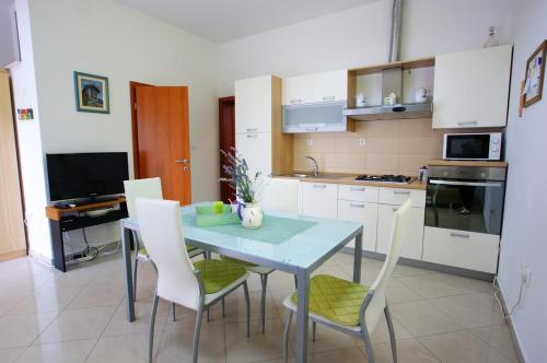 uma cozinha com uma mesa e cadeiras numa cozinha em Apartment Radunić em Kaštela