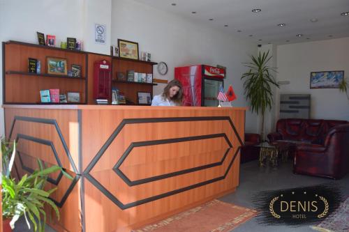 a woman standing at a counter in a store at Hotel Denis in Pristina