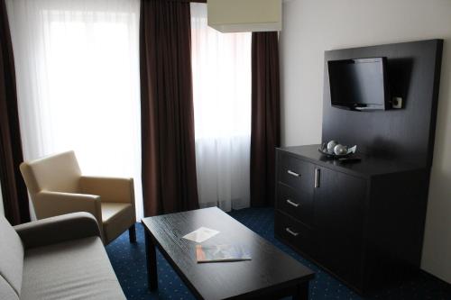 a hotel room with a couch and a tv and a table at Weinhaus Wöhler in Schwerin
