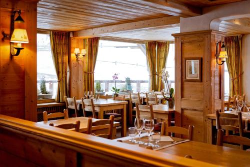 クールシュヴェルにあるホテルレ フロコンスの木製の壁とテーブルと椅子が備わるレストラン
