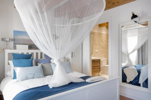 a bedroom with a white bed with blue and white pillows at Casa de Mi Abuela Ribera del Duero in Roa