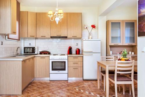 a kitchen with white appliances and a table with chairs at Sunset Villas in Possidi