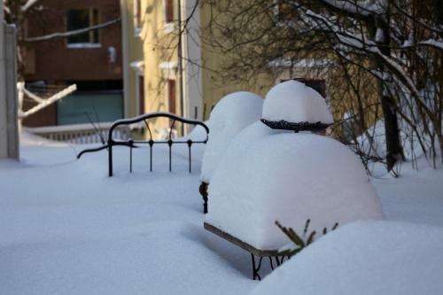 two benches covered in snow in a yard at Prästgatanett Apartments in Östersund