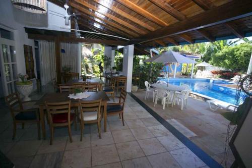 a patio with a table and chairs and a pool at Pousada Vitória in Ilhéus