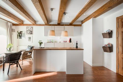 a kitchen and dining room with white walls and wooden ceilings at Casa de Mi Abuela Ribera del Duero in Roa