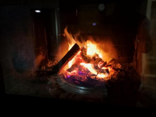 a fire in a brick fireplace at night at Hotel Edelweiss & SPA in Cesana Torinese