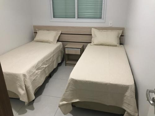 2 camas en una habitación pequeña con ventana en Apartamento de 3 Quartos na Praia dos Ingleses, en Florianópolis