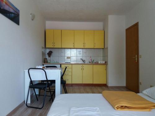a room with a bed and a kitchen with yellow cabinets at Apartment Perica in Omiš