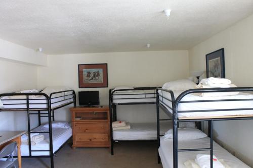 a dorm room with three bunk beds and a desk at Whitney Portal Hotel And Hostel in Lone Pine