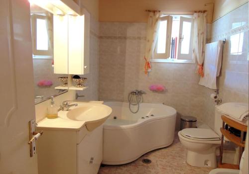 a bathroom with a tub and a sink and a toilet at Paradise House in Liapades